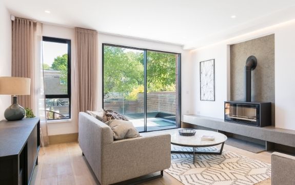 neutral tone living room with a two pane sliding glass door leading to a balcony and a casement window neutral tone living room with a two pane sliding glass door leading to a balcony and a casement window