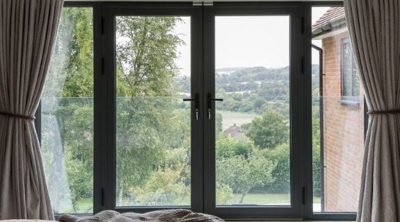 internal view of a contemporary juliet balcony with a belgian door design of casement doors and sidelights three pane black bifold door with tall fixed casement windows