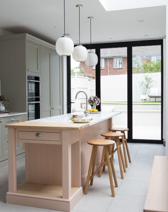 double height modern home extension with a pastel kitchen and contrasting black bifold door frames double height modern home extension with a pastel kitchen and contrasting black bifold door frames